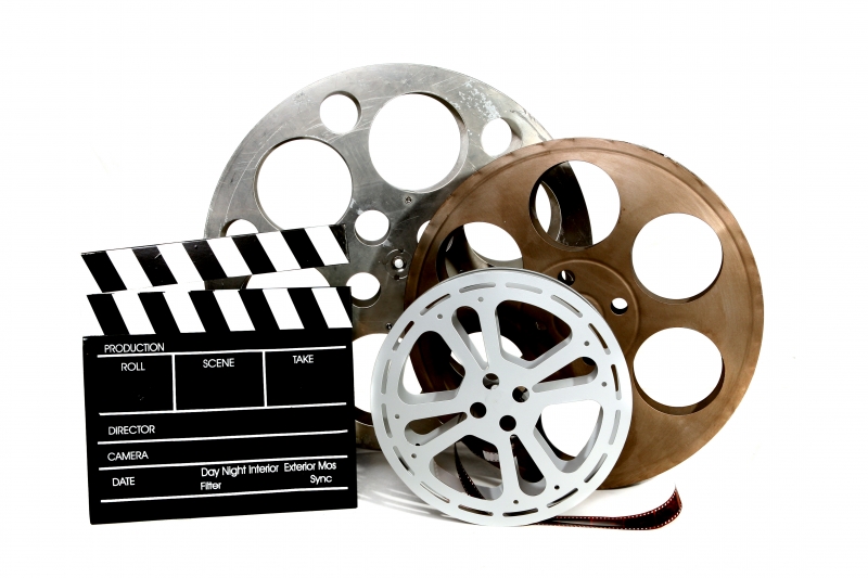 movie-production-clapper-and-film-tins-on-white